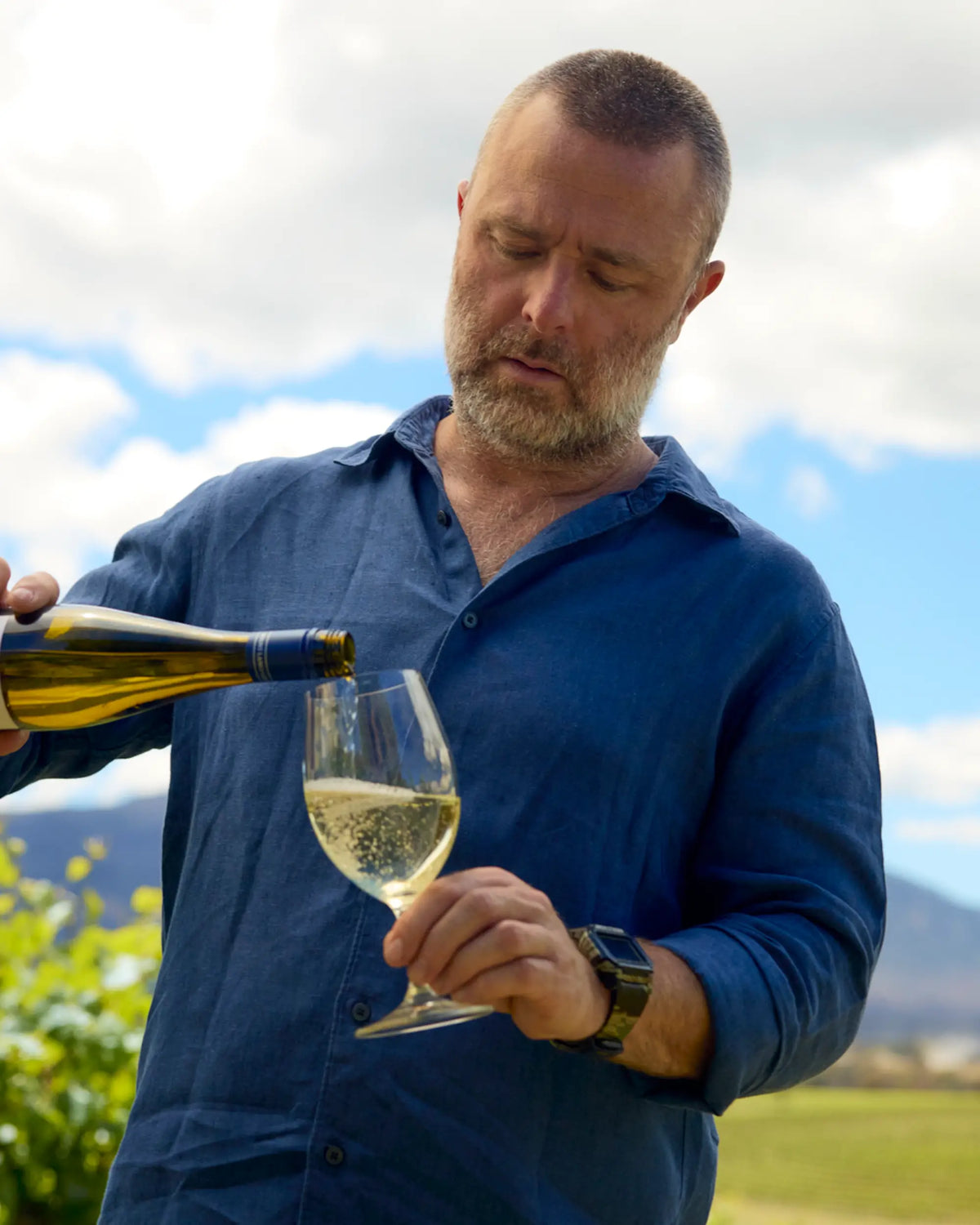 Portrait of Adam Louder, a member of the Mount Langi Ghiran team, pouring white wine outdoors