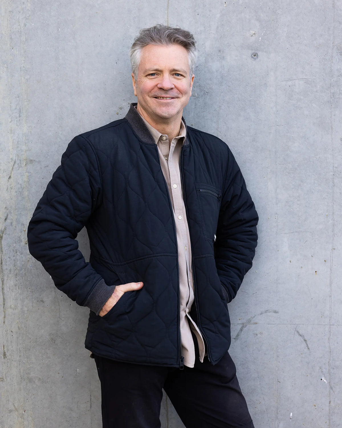 Portrait of Darren Rathbone, a member of the Mount Langi Ghiran team, smiling against a concrete wall
