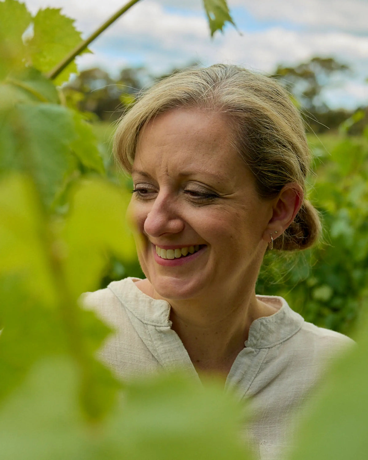 Portrait of Liz Ladhams, a member of the Mount Langi Ghiran team, smiling among vineyard leaves