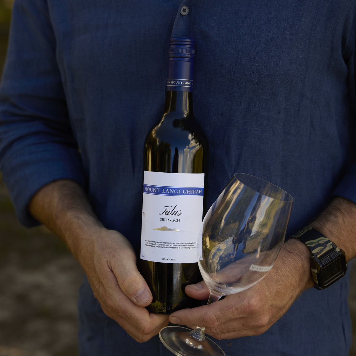 Talus Shiraz in hands with wine glass