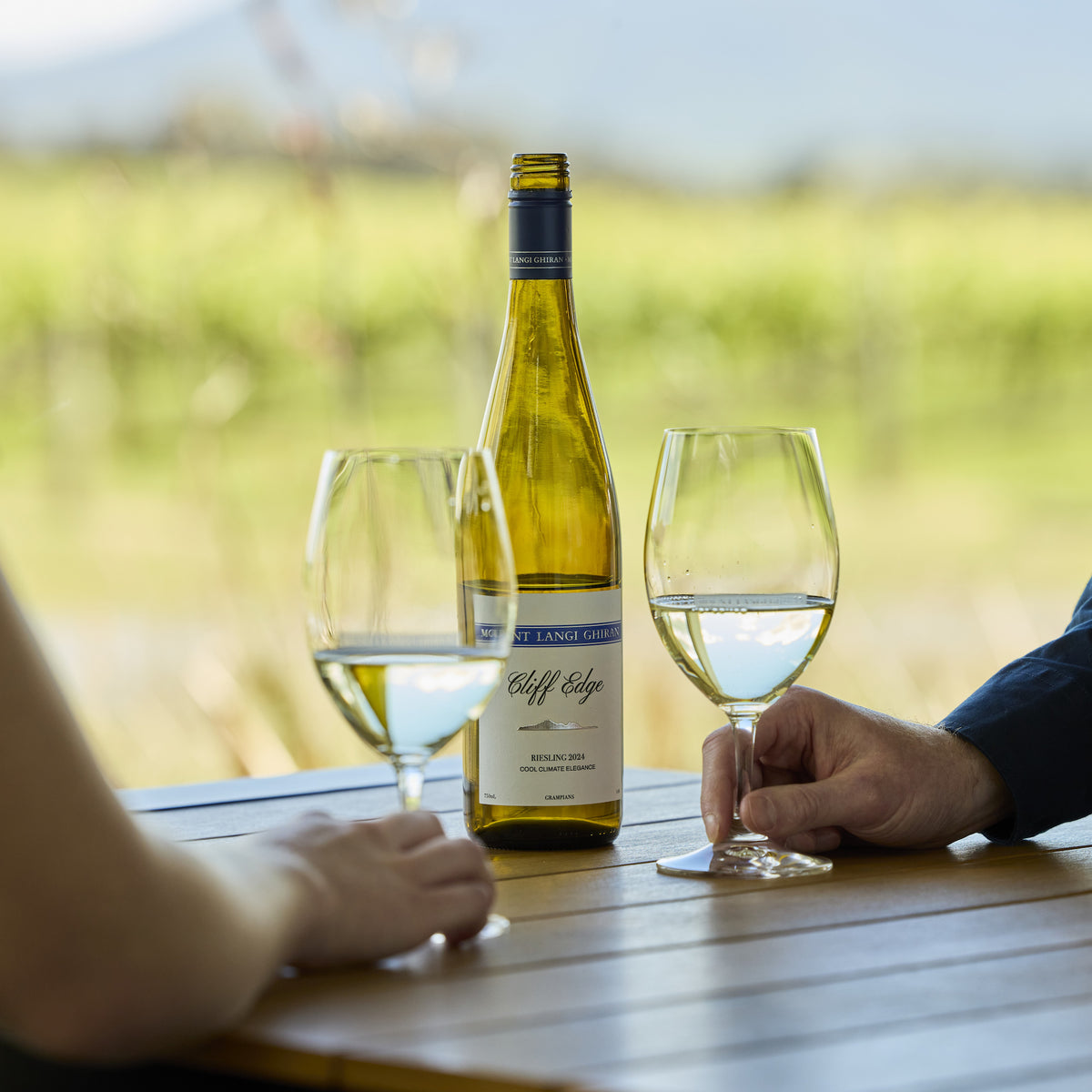 Cliff Edge Rieslng with two glasses infront of vineyards