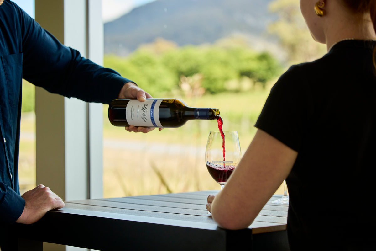 Pouring red wine from a Langi Cliff Edge bottle into a glass