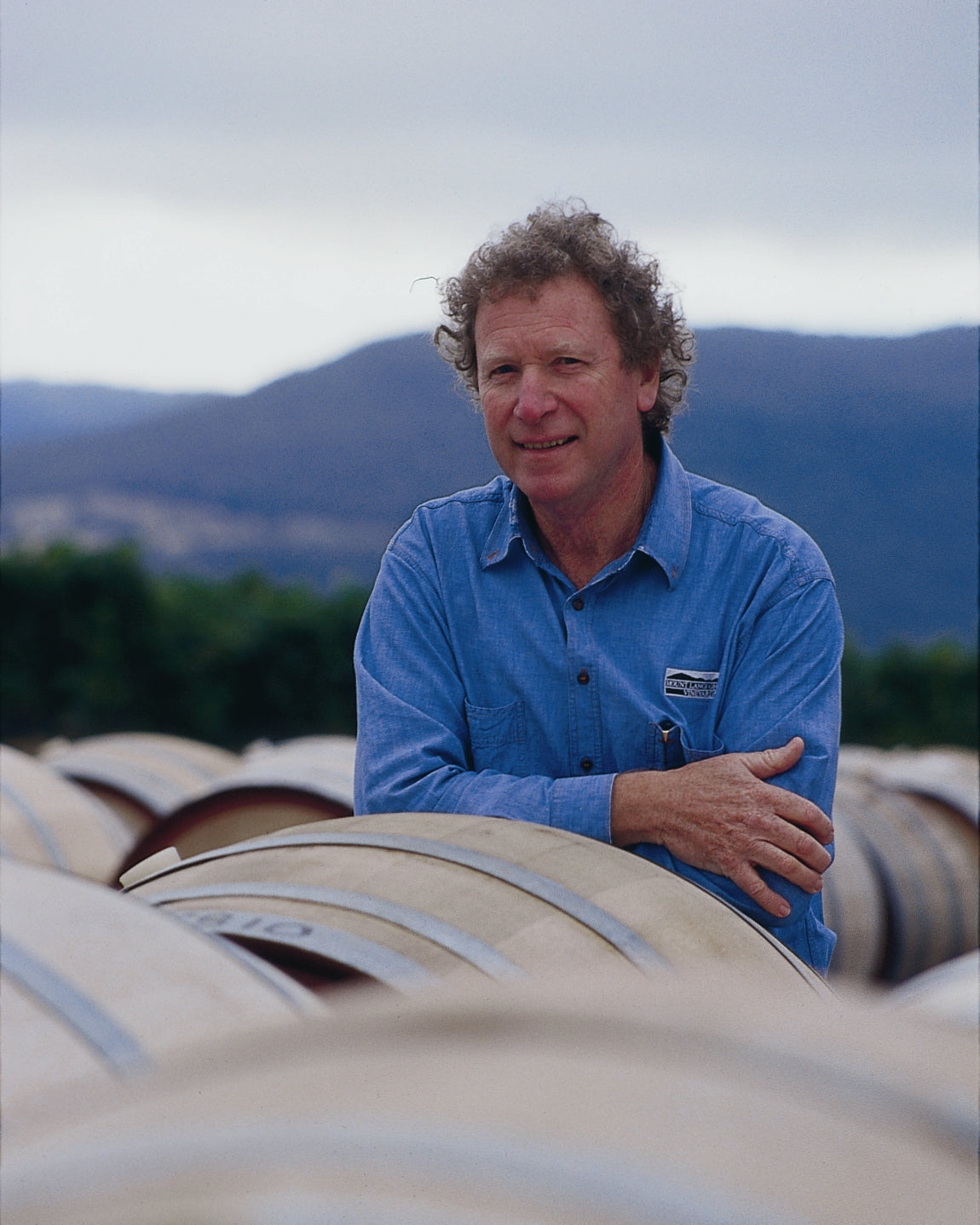 Trevor Mast resting on wine barrel infront of Mount Langi Ghiran