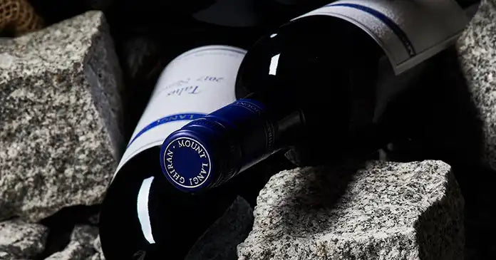 Bottle of Mount Langi Ghiran wine lying on granite rocks in moody dark lighting